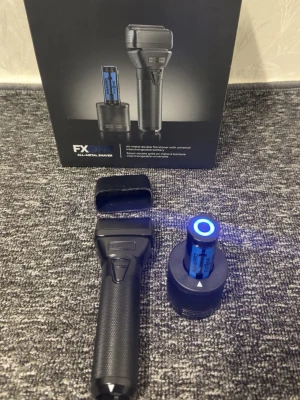 BaBylissPRO FXONE elektrisk rakapparat - Säljer en svart BaBylissPRO FXONE elektrisk rakapparat i metall med texturerat handtag för bra grepp. Medföljer laddstation och utbytbar battericylinder med blå LED-indikator. Perfekt för smidig rakning och enkel laddning.