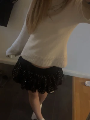 Svart glittrig volangkjol - Säljer en svart kortkjol med glittriga paljetter och volang. Kjolen har en tight passform upptill och voluminös volang nedtill som ger en festlig look. Säljs inte längre💞