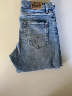 Ljusblå jeans från Replay Storlek 16A  Använda få gånger  - Snygga ljusblå jeans från Replay med klassisk femficksdesign och diskret logga på fickan. Jeansen har en rak passform och är tillverkade i mjukt denimtyg som ger en avslappnad look. Perfekta för dig som gillar en stilren och trendig vibe.