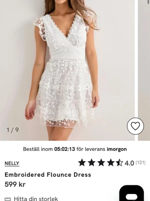 Vit klänning Nelly - Söt vit kortklänning från Nelly med broderade blommor, omlott upptill och volangdetaljer. Perfekt för studenten, midsommar eller bara i sommar!🥰