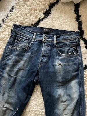  Replay Anbass - Taggen är borta men skulle gissa på storlek 29-30/30Säljer ett par blå jeans från Replay med snygga slitningar och detaljerade sömmar. Jeansen har klassisk femficksdesign och en något smalare passform. Perfekta för dig som gillar en avslappnad och trendig stil.