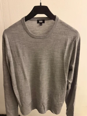 Merinoulltröja från Uniqlo - Snygg och tunn grå tröja i merinoull från Uniqlo. Klassisk rund halsringning och lång ärm, perfekt för lager-på-lager eller som den är. Enkel och stilren design som passar till det mesta.