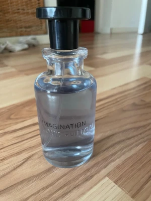 Louis Vuitton Imagination parfym - parfym från Louis Vuitton i modellen Imagination. Flaskan är genomskinlig med svart lock och har en stilren, rund form. Parfymen har en lätt blåaktig ton och flaskan är tillverkad i glas med ingraverad logga. Perfekt till sommaren 