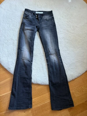 Grå bootcut jeans från Bershka - Snygga grå bootcut jeans från Bershka med slitningar och två knappar i midjan. Jeansen har en tvättad look och klassiska fem fickor. Perfekta för dig som gillar en trendig och avslappnad stil.