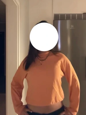 Orange färgad hoodie i bomull - Säljer en persikofärgad hoodie i mjuk bomull med klassisk passform och långa ärmar. Hoodien har ribbade muddar vid ärmslut och midja. Perfekt för en chill och avslappnad stil.