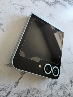 Samsung Galaxy Z Flip6 mintgrön - Säljer en Samsung Galaxy Z Flip6 i snygg mintgrön färg. Telefonen har vikbar design, två kameror på utsidan och en stor yttre skärm. Tillverkad i glas och metall med stilrena linjer och modern känsla. Batterihälsa 97%, batteri och skärm utbytta hos samsung center. Medföljer flera skal.