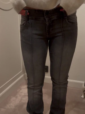 Mörkgrå bootcut jeans med sömm från Bershka🍒 - Snygga mörkgrå bootcut jeans med markerade vertikala sömmar framtill. Jeansen har klassisk femficksdesign och normal midja med två knappar. Perfekta för en trendig och stilren look.