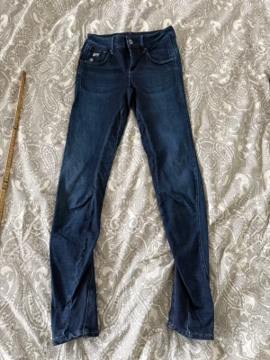 Mörkblå skinny jeans med stretch från G-Star - Snygga mörkblå skinny jeans med klassisk femficksdesign och stretchigt material för skön passform. Jeansen har normal midja och smala ben, perfekta till vardagslooken. Längden är cirka 75 cm från innerbenet.