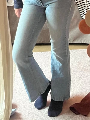 Ljusblå bootcut jeans med rå kant - Snygga ljusblå bootcut jeans med rå, fransad kant nertill. Jeansen har klassisk femficksdesign och är tillverkade i denim med lätt stretch. Perfekta för en avslappnad och trendig look. Har en nästan osynlig orange fläck vid inre sömmen men den ser man inte! 🌸🌸🌸