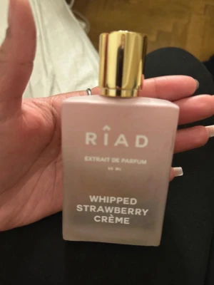 Riad Whipped Strawberry Crème parfym - Riad Whipped Strawberry Crème Extrait de Parfum i en stilren, matt rosa glasflaska med guldfärgad kork. Doften har en söt och fruktig karaktär med inslag av jordgubbskräm. Flaskan rymmer 50 ml och har en modern, lyxig känsla. Köpt för 1200kr på riad och har använt ca helftän