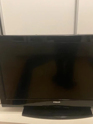 Svart platt-TV från Finlux - En svart platt-TV från Finlux med stilren design och bred skärm. TV:n har en rektangulär form och står på en stabil fot. Perfekt för filmkvällar eller gamingrummet. Passar bra i de flesta rum tack vare sin enkla och moderna look.
