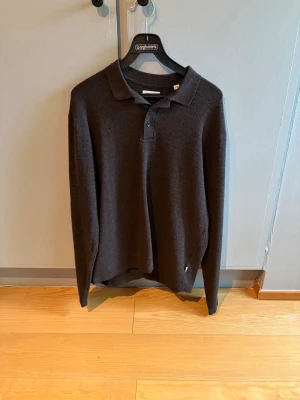 Mörkbrun stickad pikétröja Jack & Jones - Snygg mörkbrun stickad pikétröja från Jack & Jones med krage och knappar framtill. Tröjan är använd endast en gång.