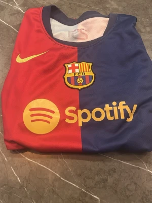 FC Barcelona matchtröja Nike - Snygg FC Barcelona matchtröja i rött och blått med klubbmärke, Nike-logga och Spotify som sponsor framtill. Tillverkad i lätt och ventilerande material, perfekt för fotbollsträning eller att bära på läktaren.