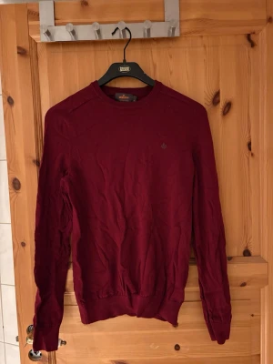 Vinröd tröja från morris - Vinröd tröja från morris med rund halsringning och diskret logga broderad på bröstet. Tröjan har långa ärmar och ribbade muddar vid ärmslut och nederkant. Perfekt för lager på lager och enkel att matcha med jeans eller chinos.