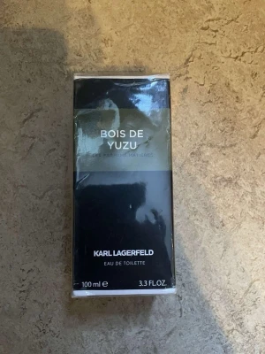 Karl Lagerfeld Bois de Yuzu parfym - En stilren parfym från Karl Lagerfeld, Bois de Yuzu, i en svart och olivgrön rektangulär förpackning. Eau de toilette, 100 ml. Modern och elegant design som passar dig som gillar fräscha och träiga dofter.