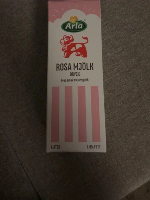 Arla Rosa Mjölk jordgubb 1L - En 1 liters förpackning Arla Rosa Mjölk med smak av jordgubb. Kartongen är vit med rosa detaljer och har en illustration av en rosa ko. Innehåller 1,0% fett och är en smaksatt mjölkdryck. Inget inuti utan bara förpackning 