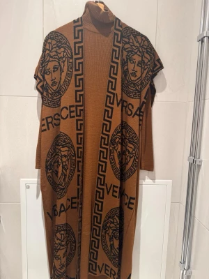 Brun lång klänning med kofta till  - Snygg brun lång kofta med klänning undertill. Materialet är stickat och känns mjukt och lyxigt. Perfekt för att ge din outfit en exklusiv touch.