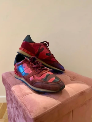 Valentino Rockrunners röda - Säljer ett par Valentino Rockrunners med camo-mönster i olika nyanser av rött och svart. Skorna har detaljer i mocka och läder, samt nitar på hälen. Dustbag ingår✅Storlek 41.