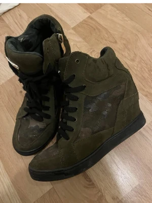 Olivgröna camo high top sneakers - Säljer ett par olivgröna high top sneakers med svart sula och svarta skosnören. Storlek 38