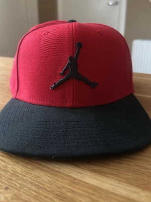 Röd och svart Jordan keps - Den är helt ny inte använd. Inga märken eller inget slitet märke. Den är riktig, visar i bak att den är riktig.