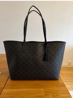Svart shoppingväska med mönster - Säljer denna superfina väskan från Malene Birger🤎Har några slitningar på utsidan samt en del inuti (se bilder) Nypris är 2800kr