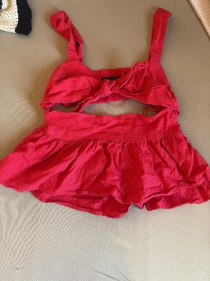 Rosa linnetopp med knyt från Zara - Snygg rosa linnetopp från Zara med breda axelband och knyt framtill. Toppen är croppad och har en luftig, somrig känsla med volangdetalj nedtill. Perfekt för varma dagar och enkel att styla med shorts eller kjol. Aldrig använd