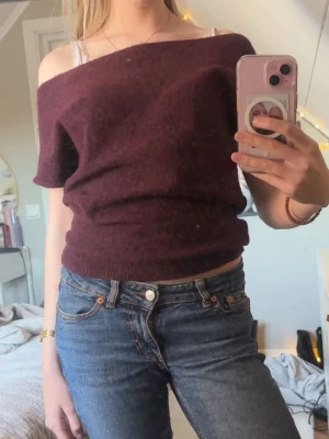 Vinröd off shoulder stickad tröja - Mysig vinröd stickad tröja med off shoulder-design och korta ärmar. Tröjan har en bred halsringning och ribbad nederkant. Perfekt att styla med jeans för en avslappnad men trendig look.🩷🩷