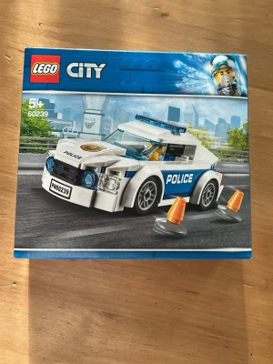 LEGO City Polisbil  - LEGO City set 60239 med en vit och blå polisbil, två orange koner och en polisfigur. Setet är av plast och passar för barn från 5 år. Perfekt för dig som gillar att bygga och leka med stadsmiljöer och fordon.