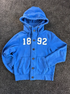 Blå Vintage Abercrombie & Fitch Hoodie - Säljer nu denna sjukt feta vintage Abercrombie & Fitch hoodien! Mycket fint skick, inga defekter. Storlek XL i muscle passform, men sitter som en M/L! Väldigt eftertraktad och svår att få tag på. Hör av er vid minsta fundering, pris går att diskuteras 🤝