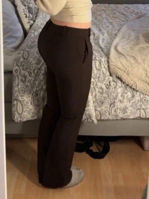 Bruna kostymbyxor med pressveck - Säljer ett par bruna kostymbyxor med raka ben från bikbok. Byxorna har låg midja, bälteshällor och sidofickor. Perfekta för en clean och stilren look. Använda 2 gånger, nypris 499kr. 