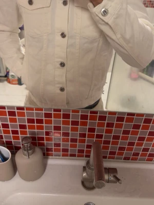 Vit overshirt jacka  - Snygg vit jeansjacka med klassisk krage och silverfärgade knappar framtill. Två bröstfickor med lock och knappdetaljer. Rak passform och långa ärmar. Perfekt för dig som vill ha en stilren och fräsch look.