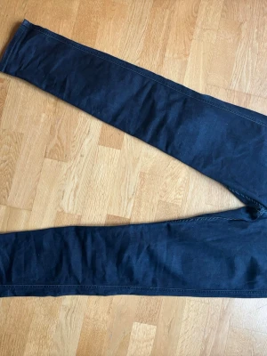 Mörkblå skinny jeans anbass hyperflex - Snygga mörkblå skinny jeans med klassisk femficksdesign och smal passform. Jeansen har en stilren look och är perfekta för dig som gillar en enkel men trendig stil. Materialet är stretchigt för extra komfort. Säljer för det är för litet. Inga fläckar. Waist 33 length 34. Nypris 1500 säljer för 350