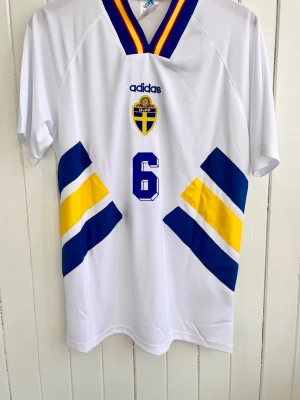 Stefan Schwarz - Sverige - VM 1994 - Säljer en klassiska fotbollströja, Stefan Schwarz svenska vita vita bortamatchtröja från VM 1994 i USA. Tröjan är en reprint i nyskick.  Aldrig använd.  Storlek: Medium