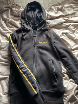 Svart aik Hoodie från 515 - Svart hoodie med norra stå på bröstet gul o grå aik design längs armarna