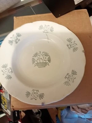 Gammal djup tallrik Tulpan - Vit djup tallrik från Rörstrandmed grönt blommönster och motiv av en korg med blommor i mitten. Tallriken har vågig kant och mönstret heter Tulpan. Tillverkad i porslin och har upphängningsanordning på baksidan.