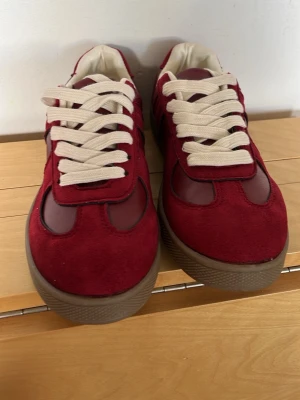 Masion margela  - Snygga vinröda sneakers med ovandel i mocka och textil, vita breda skosnören och bruna gummisulor. Skorna har en klassisk låg profil och stilrena detaljer som passar till många olika outfits. Vet inte riktigt vad för märke kan vara hm men inte säker, priset kan diskuteras med snabb affär💕🌸