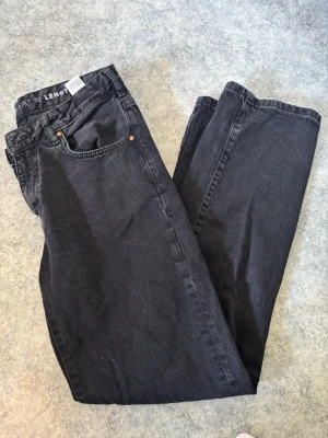 Svarta raka jeans från bikbok - Svarta jeans från bikbok med rak passform. Använda sparsamt och sytt dit en extra knapp då dom var för stora för mig. Perfekta för en avslappnad och stilren look.