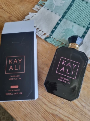 Kayali Oudgasm Rose Oud parfym - Kayali Oudgasm Rose Oud är en exklusiv parfym i en elegant svart flaska med guld- och rosa detaljer. Flaskan har en geometrisk form och matchande svart lock. Doften är en Eau de Parfum och flaskan rymmer 100 ml.