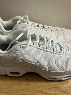 Nike Air Max Plus vita sneakers - Nike Air Max Plus sneakers i helvitt med mesh-överdel och syntetiska detaljer. Snygg vågig design på ovandelen, synlig Air Max-dämpning i sulan och klassisk Swoosh-logga på sidan. Perfekta för dig som gillar sportig och clean stil.