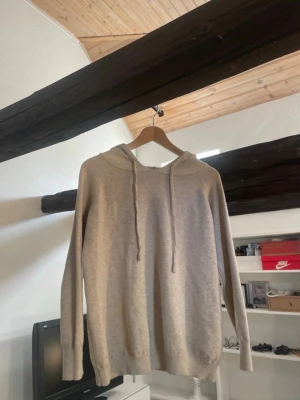 Beige hoodie  - En stilren beige hoodie med huva . Hoodien har långa ärmar och ribbade muddar vid ärmslut och nederkant. Perfekt för en avslappnad look och enkel att matcha med andra plagg.
