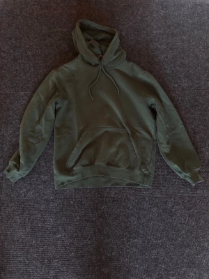 H&M Hoodie relaxed fit grön - Snygg olivgrön hoodie med klassisk huva och dragsko. Hoodien har en stor magficka framtill och ribbade muddar vid ärmslut och nederkant. Perfekt för en avslappnad streetstyle-look. Materialet känns mjukt och bekvämt mot huden. Hoodien är gott använd. OBS! Uppfattas mer blek på bilden än vad den verkligen är. Tveka inte på att höra av dig för att ställa fler frågor! Är öppen för pris förslag👍