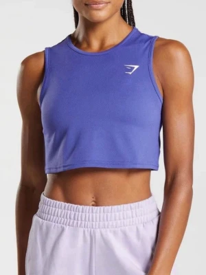 Lila crop top från Gymshark - Snygg lila crop top från Gymshark med rund halsringning och ärmlös design. Tillverkad i ett stretchigt funktionsmaterial som passar perfekt till träning. Diskret logga på bröstet för en sportig look.