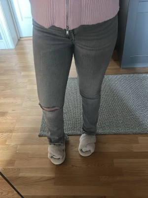Grå slitna jeans med hål på knät - Säljer ett par grå jeans från Zara med rak passform, slits på insidorna och ett stort hål på vänster knä. Dem är högmidjade men god potential till att göras om. De är även uppsprättade längst ner och passar mig som är 163cm. Fler bilder kan fås!💗