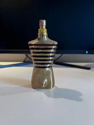 Le Male Elixir Parfym 125ml Gaultier - Jean Paul Gaultier Le Male Elixir är en parfym i en ikonisk flaska formad som en manlig torso. Flaskan är guldig med svarta horisontella ränder och har en metallisk finish. Parfymen är tillverkad i Frankrike och rymmer 125 ml. Jag skulle anta att det är runt 110 ml kvar i den. Dessvärre har jag inte kvar foten som den står i eller burken man fick den i. Hör av er vid frågor!