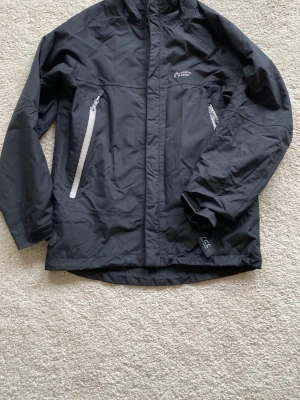 North Bend Vårjacka  - Svart vindjacka från North Bend med två vita dragkedjeförsedda fickor framtill och hög krage. Jackan har diskret logga på bröstet och är tillverkad i ett lätt, vindtätt andningaktiv material. Perfekt för blåsiga dagar och enkel att matcha med olika outfits.