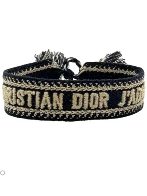 Dior armband  - Snyggt broderat armband från Christian Dior i marinblått och beige. Armbandet har texten 'Christian Dior J'Adior' och avslutas med dekorativa tofsar. Tillverkat i textil med en bred, mjuk design som ger en trendig och exklusiv känsla.