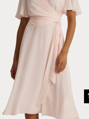 Lauten ralph lauren Ljusrosa omlottklänning med knyt - Säljer en ljusrosa omlottklänning med knyt i midjan och korta, fladdriga ärmar. Klänningen har en mjuk, flowy passform och är tillverkad i ett tunt, skönt material som passar perfekt till sommaren. Enkel men elegant design som ger en romantisk känsla. Strl 42 (10)