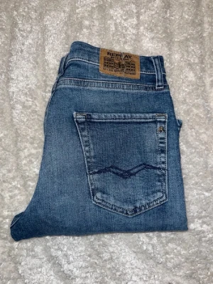 Replay jeans  - Replay jeans i klassisk blå färg och vida ben. Midja 35cm, längd 93cm. Obs jeansen har bruna fläckar - se bild. Jeansen är i barnstorlek för 14år. Jag skulle bedöma att dom passar W27 L30 - men utgå efter mått. JAG SKICKAR EJ FLER BILDER NÄR JAG BÄR JEANSEN! för bättre inblick i passformen rekommenderar jag att googla på modellnamnet. För storleksguide kolla måtten noggrant då jeansen alltid kan vara uppsydda heller krympta och jag ej tar emot returer :) s6,4