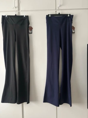 Bootcut träningsbyxor svart & blå - Två par bootcut träningsbyxor i svart och mörkblått. Byxorna är utsvängda ben, perfekta för gymmet eller yoga. Tillverkade i ett stretchigt och mjukt material som ger bra rörelsefrihet. Snygg och enkel design utan synliga loggor. Storleken 170/xxs. Säljer 1 för 80 och båda för 160