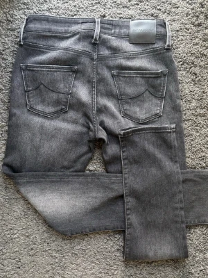 Jacob Cohën - W27 Exklusiva Grå Jeans - Made in Italy - Unik Jacob Cohën lyxdenim i mörkgrå tvätt med snygga fades, premium rakt igenom. Jeansen är dammodell men passar även killar som gillar slim fit. 🧵 Jacob Cohën – Kimberly. 📏 Storlek W27 med slim fit passform. 🧩 Premium denim med skön comfort-stretch och mycket hög komfort. 📐 Mått: Midja 35,5 cm, innerben 73,5 cm, ytterben 100 cm. ✅ Skick 9/10, sparsamt använda. ✨ Läderpatch, metal-logo, citat i gylf, brodyr, Made in Italy. 💰 Nypris ca 3800 kr. 🧍‍♂️ Passar ca 174–178 cm. ‼️ Skickas inom 24 h‼️